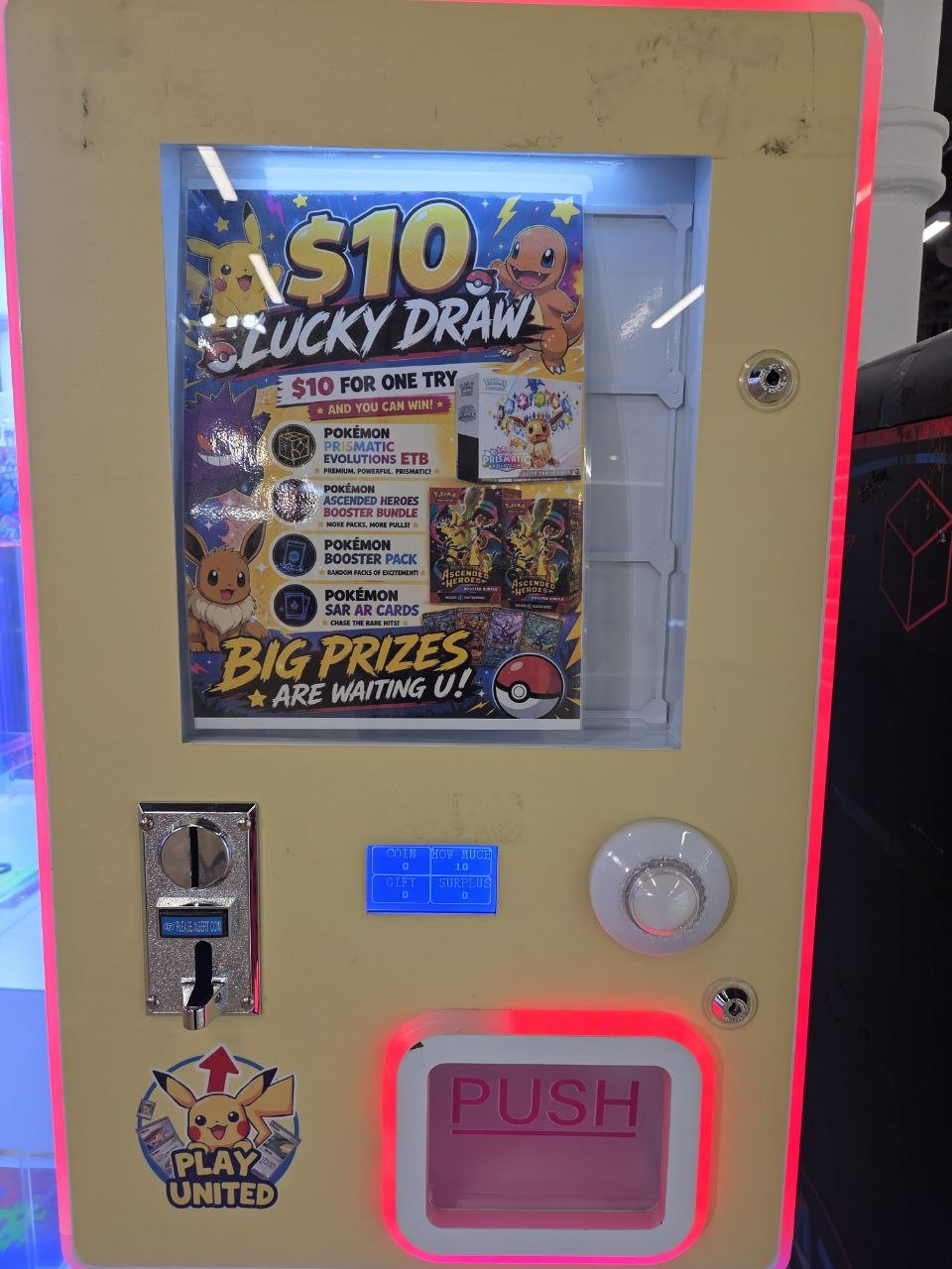 A Play United branded $10 Lucky Draw Oripa vending machine advertising Pokemon Prismatic Evolutions ETB, Ascended Heroes Booster Bundle, booster packs, and SAR AR cards as prizes